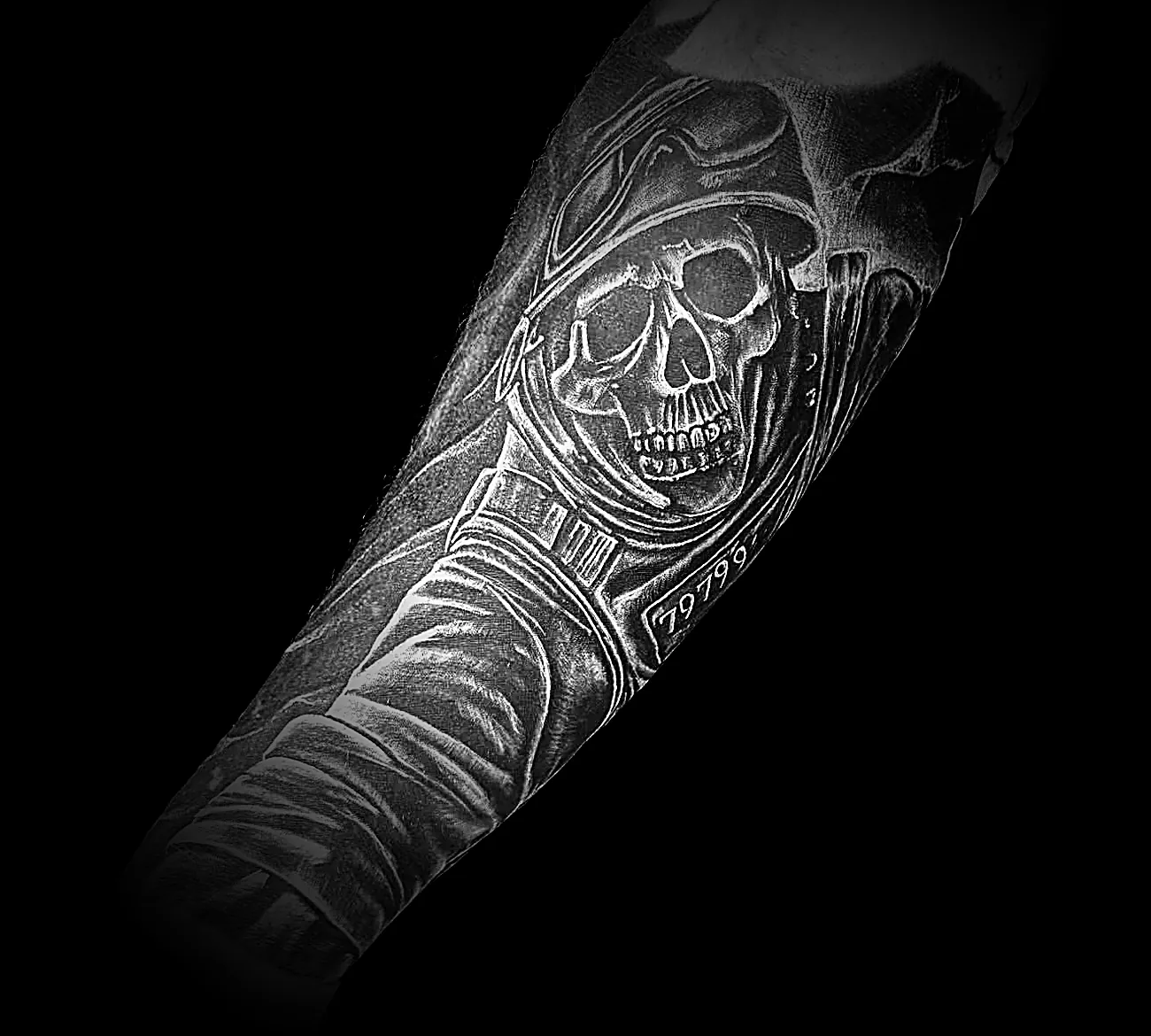 Black and grey realism forearm tattoo of a skull in a helmet, healed skin
