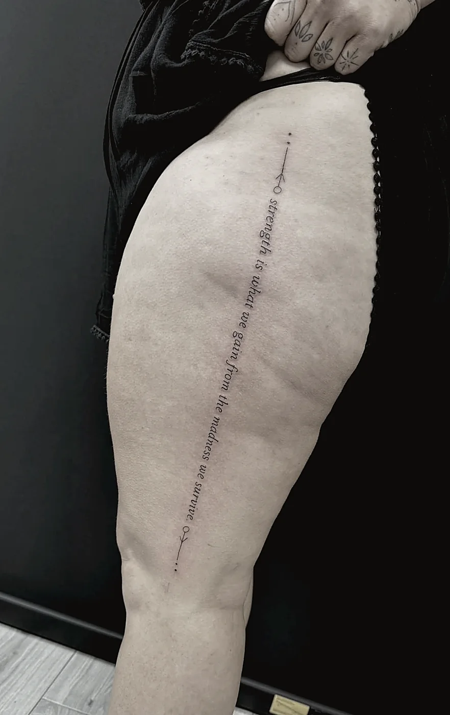 Script lettering tattoo running down the thigh